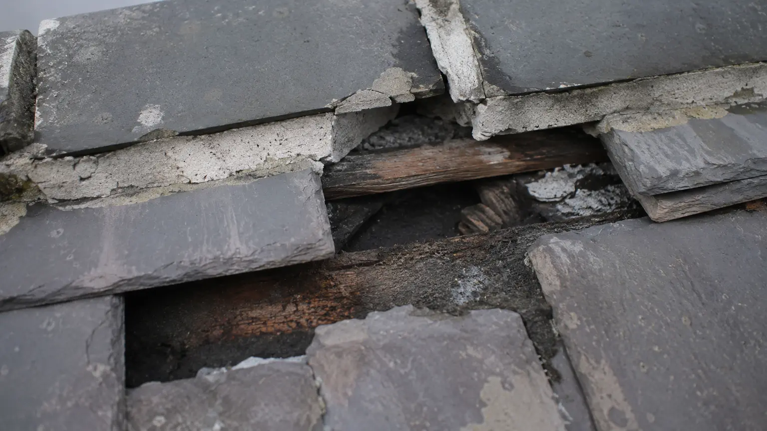 Close view of cracked and slipping slates with failing mortar on a Dublin roof